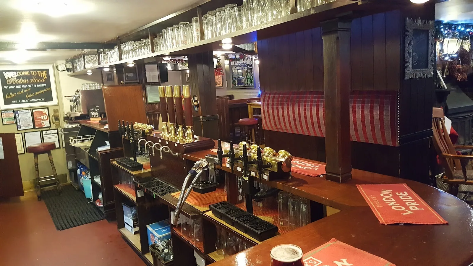 The bar at The Robin Hood, Havant, with hand pumps, London Pride bar runners and red gingham seating